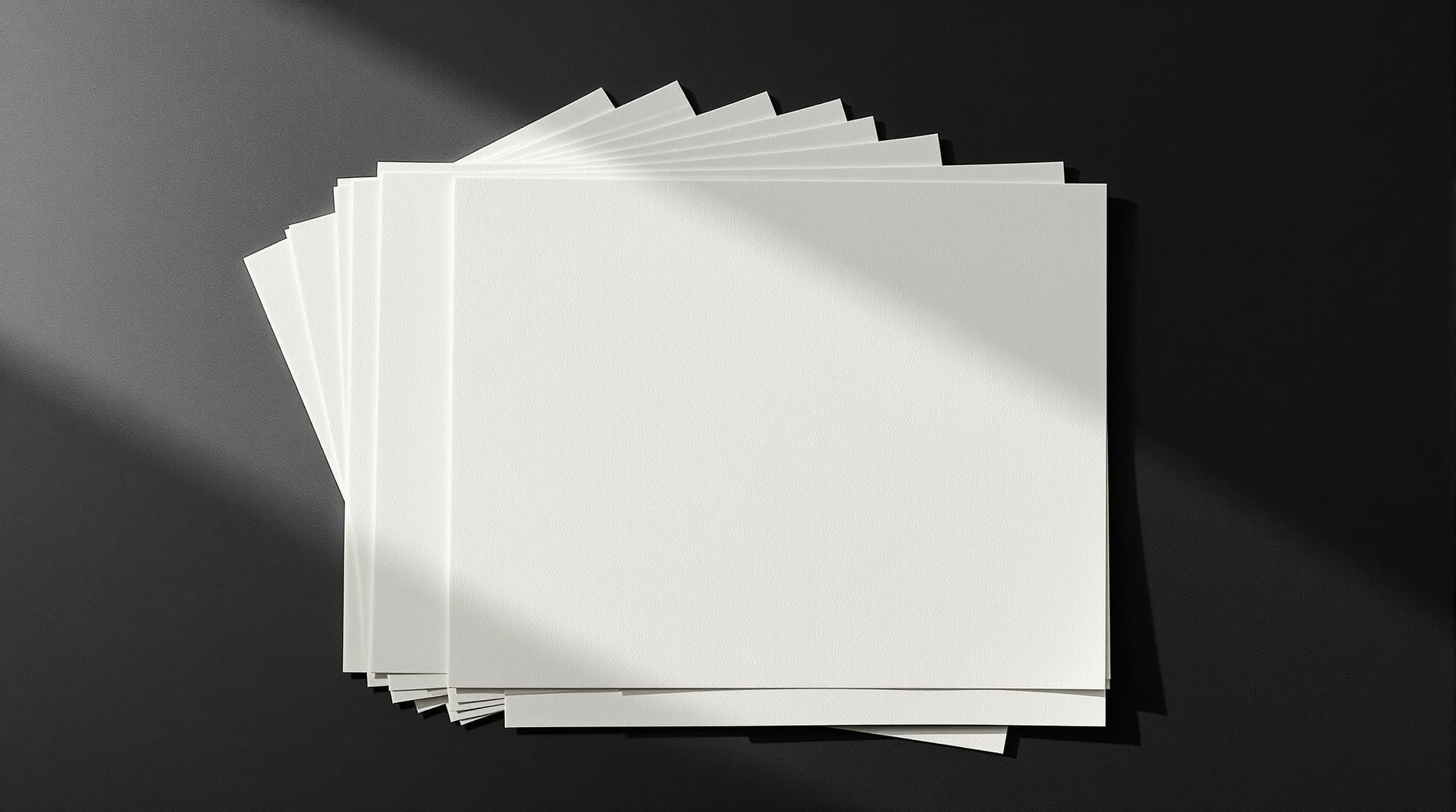 Blank newsprint sheets fanned across a dark surface