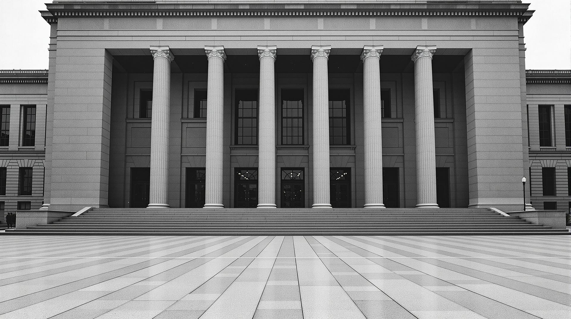 Grey stone institutional facade and empty forecourt under flat light