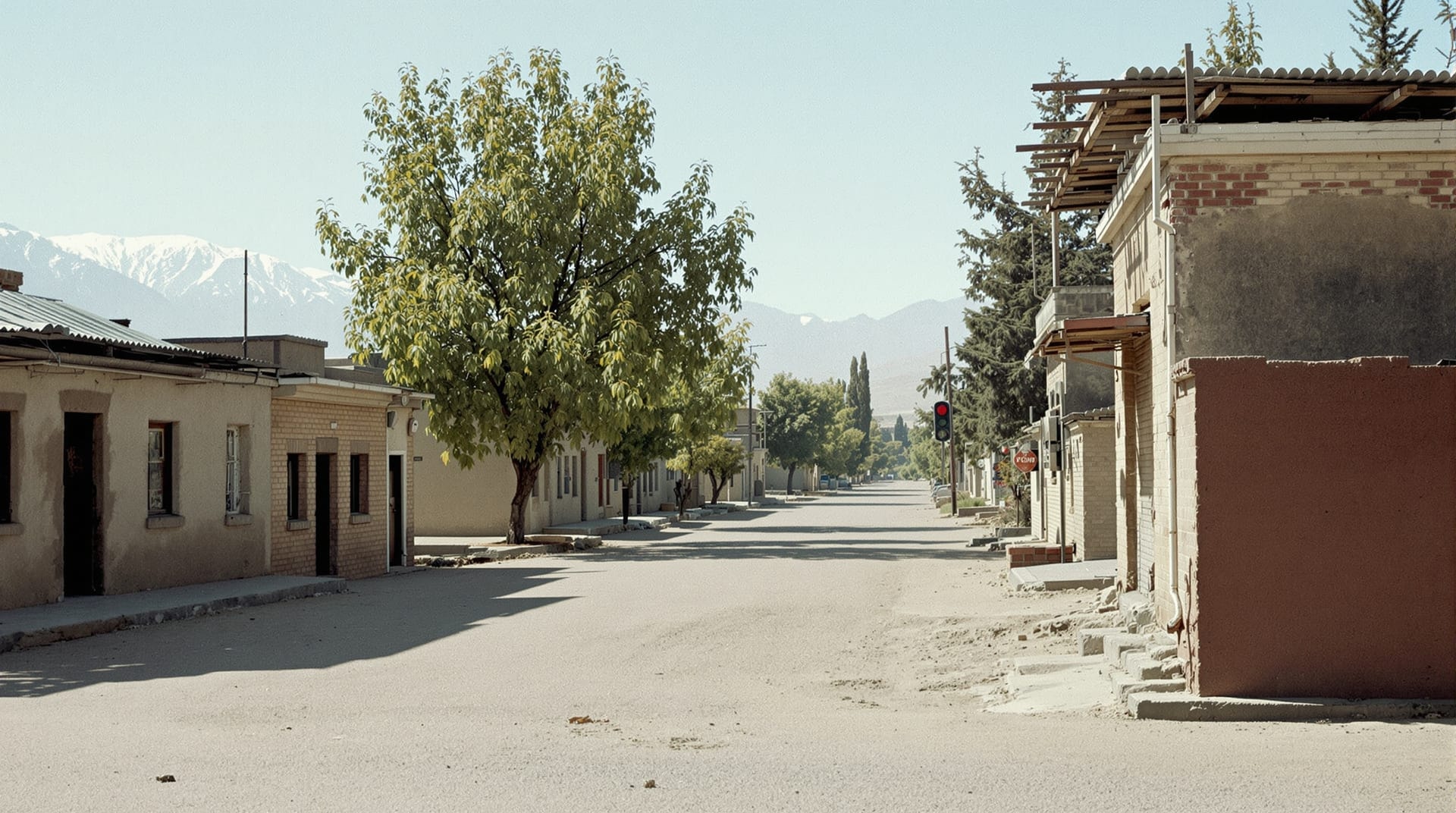 Quiet street of low buildings with fire-darkened walls and mountains beyond