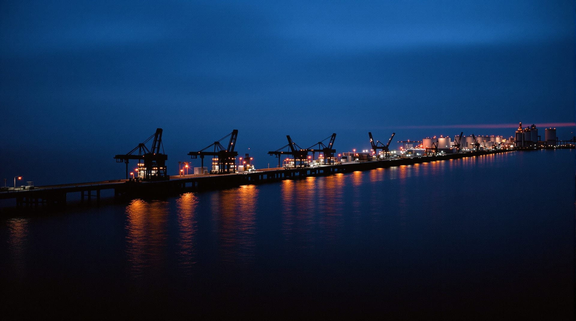 Crude oil loading jetty and storage tanks at dusk